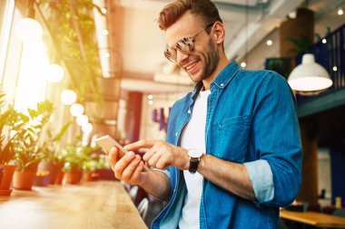 kafede otururken Smartphone kullanan genç adam