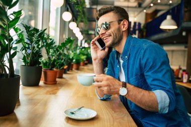 Genç adam kafede otururken Smartphone tarafından konuşma