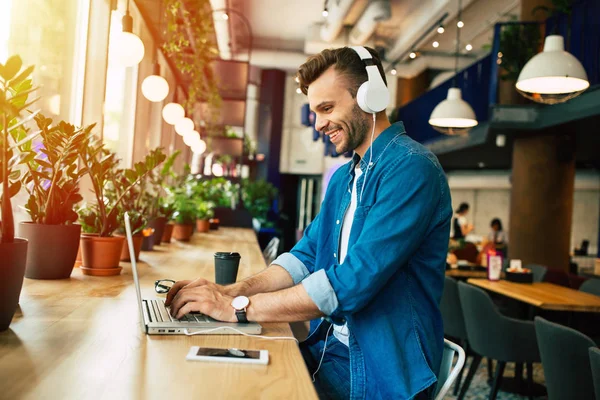 Hombre Joven Con Auriculares Trabajando Ordenador Portátil Mientras Está Sentado — Foto de Stock