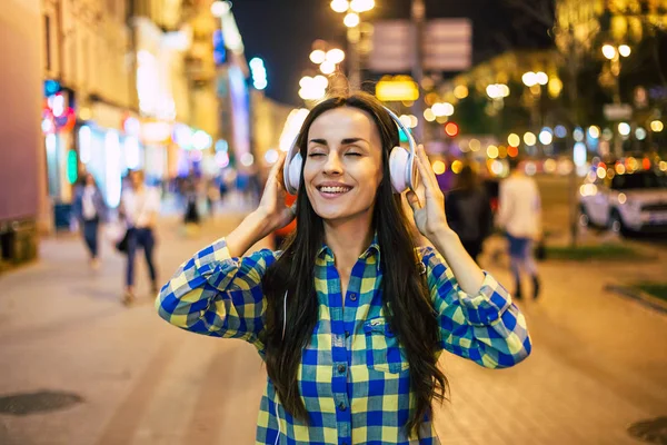 Young relaxed woman listening to music in headphones on city street
