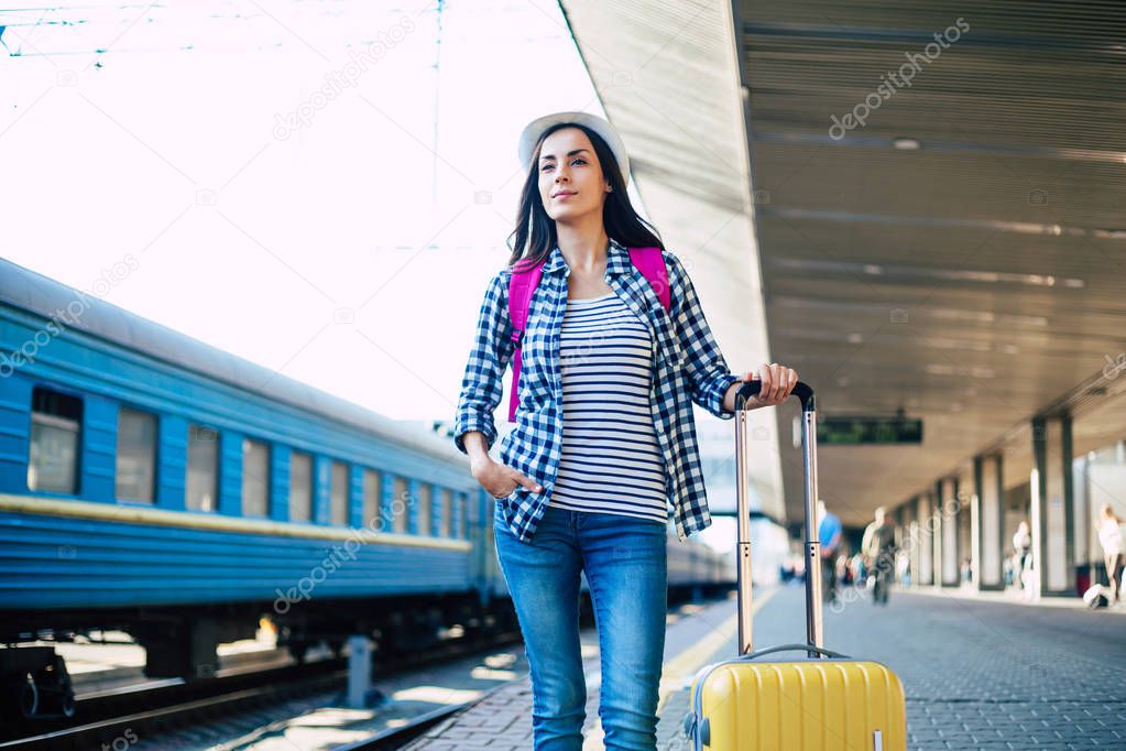 Young casual woman waiting for train on railway station