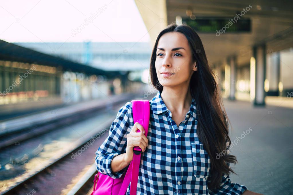 Young casual woman waiting for train on railway station