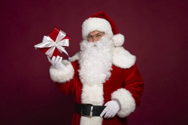 kağıt hediye kutusu tutarak ve kameraya kırmızı zemin üzerine arıyorsunuz Noel Baba kostümlü adam portresi Noel ve yeni yıl kavramı 