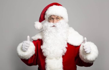 başparmak gri arka plan üzerinde gösterilen Noel Baba kostümlü adam portresi Noel ve yeni yıl kavramı 