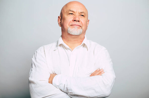 portrait of handsome bearded man in white shirt with crossed arms posing on grey background 