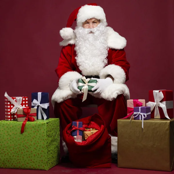 Mann Weihnachtsmann Kostüm Beschenkt Sitzen Mit Geschenksack Auf Rotem Hintergrund — Stockfoto