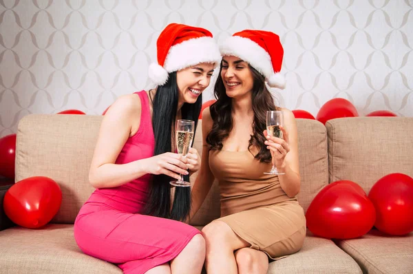 Duas Namoradas Chapéus Santa Celebrando Ano Novo Bebendo Champanhe Sala — Fotografia de Stock