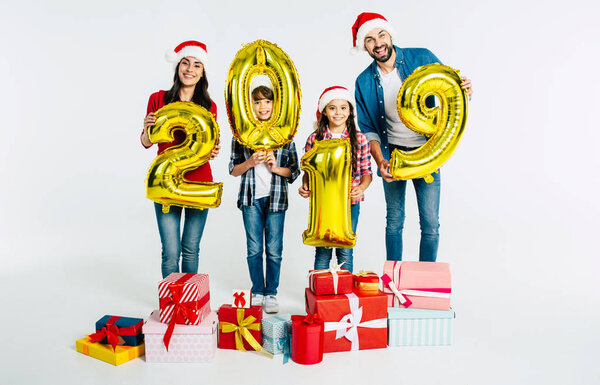 Cheerful family holding golden numbers 2019 and gift boxes on white background