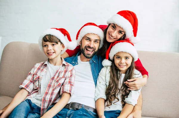 リビング ルームで過ごす時間の赤いサンタ帽子で幸せな若い家族 — ストック写真