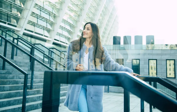 都市の背景にポーズの灰色の毛皮のコートの若い女性 — ストック写真