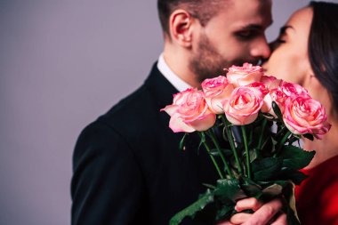 Güzel genç romantik çift onlar elinde gül buketi arkasında öpüşme fotoğrafını kapatın. St Sevgililer günü.