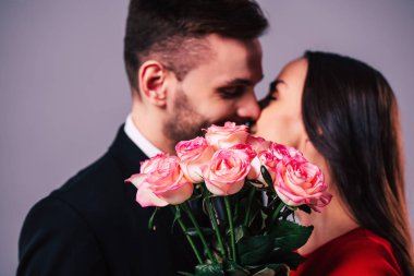 Güzel genç romantik çift onlar elinde gül buketi arkasında öpüşme fotoğrafını kapatın. St Sevgililer günü.