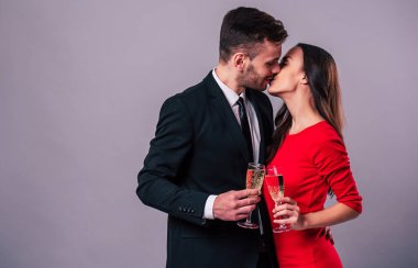 Şampanya bardağı gri arka plan üzerinde tutan mutlu romantik insanlar