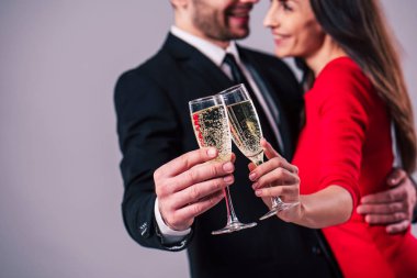 Şampanya bardağı gri arka plan üzerinde tutan mutlu romantik insanlar