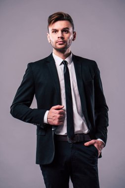 Gri arka plan üzerinde takım elbiseli yakışıklı adam
