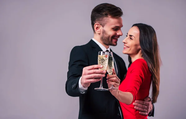 Happy romantic people holding champagne glasses on grey background
