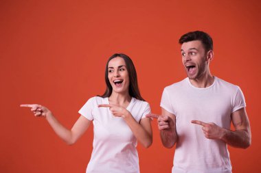 Güzel genç bir çift beyaz boş t-shirt turuncu arka plan üzerinde poz olan. İlişki, Aile, reklam