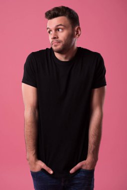 Genç utangaç ve belirsiz adam onun ellerini ceplerine tutar ve stüdyoda kameraya benziyor.