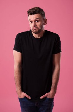 Genç utangaç ve belirsiz adam onun ellerini ceplerine tutar ve stüdyoda kameraya benziyor.