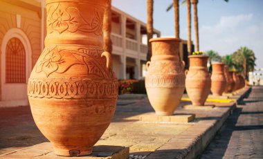 Hamurlu sürahi. Bu oyma ile loamy jugful fotoğrafını turuncu güneş ışıkları blok taş yol boyunca akşam ile ışıklı.