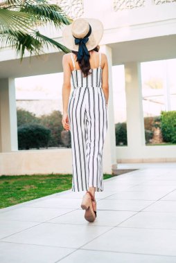 Kuş gibi özgür. Büyük uygun tulum ve deri arka kısmında bir kömür renkli yay ile takımları bir şapka virid palmiye ağacı bakan bir bodacious kadınlar peeps.