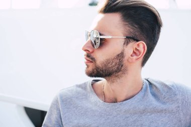 Varlığı üzerinde mükemmellik. Yüzünde ve cam yansıtan ile güneş gözlüğü takıyor parlak beyaz arka plan önünde güzel saç modeli sakallı takdire şayan adam.