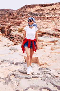 keffiyeh ve kayalık çöl sahnede poz güneş gözlüğü giyen kadın