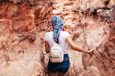 Sands. İnce ve uzun boylu kız kahverengimsi kayalar arasında ve rahat kıyafet ve bir smartphone içinde onun arka cebinde kot şort şaşırmış fotoğraf.