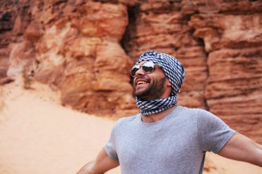 traveller wearing keffiyeh and sunglasses in desert scene clipart