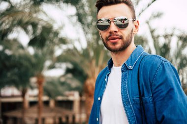 Genç adam arka plan avuç içi ile güneş gözlüğü takıyor