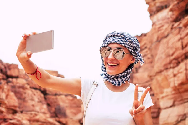 Peace to the world. Superb woman in comfortable outfit , with tanned and glowing skin, thin and elegant hands is making a selfie of herself and sending peace to the world.