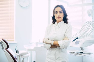 Diş hekimleri ofisi. Bir doktor bir dişçi tıbbi malzeme dolu bir elbise giyiyor ve Oda medikal eldiven önünde parlak renkli kabin içinde.
