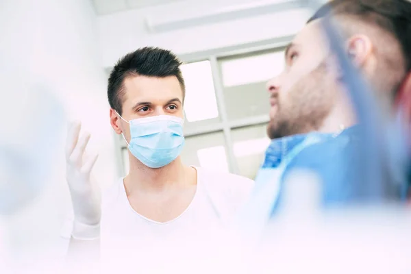 A dialogue in a dentists cabinet full of professional supplement between a doctor and a patient about the dental treatment which will be given.