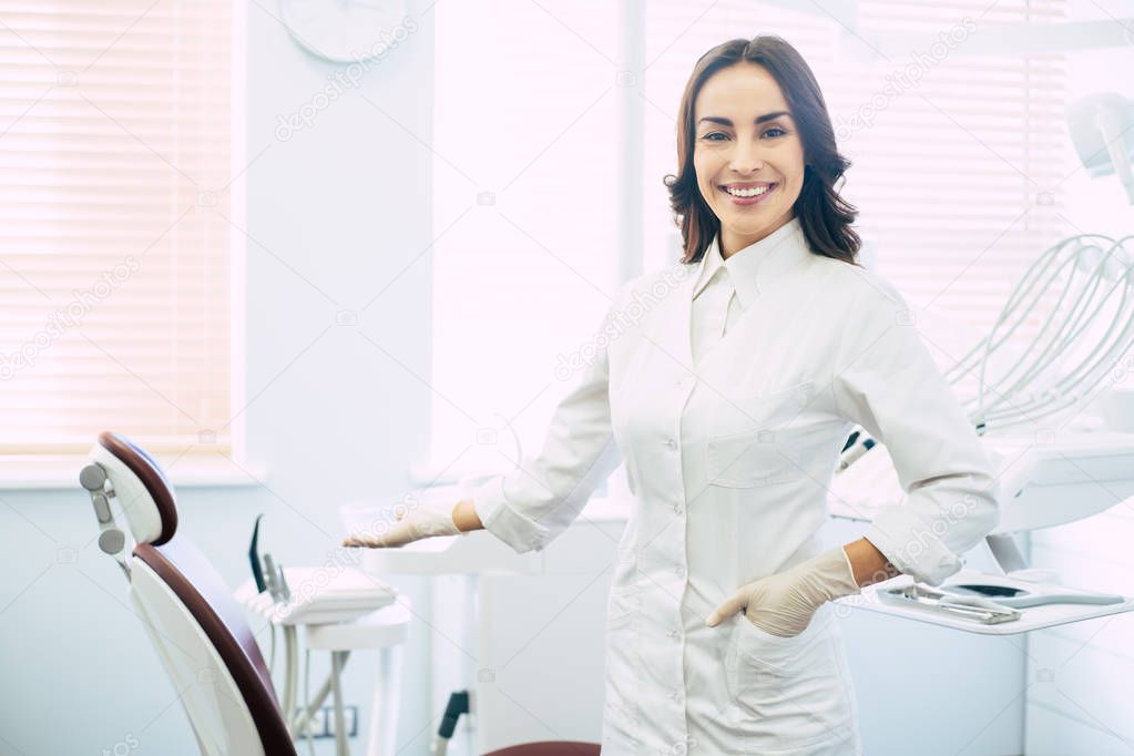 Welcome! A professional doctor in a sphere of stomatology in her dentist spacious cabinet with a special instruments and perfect atmosphere for giving a treatment.