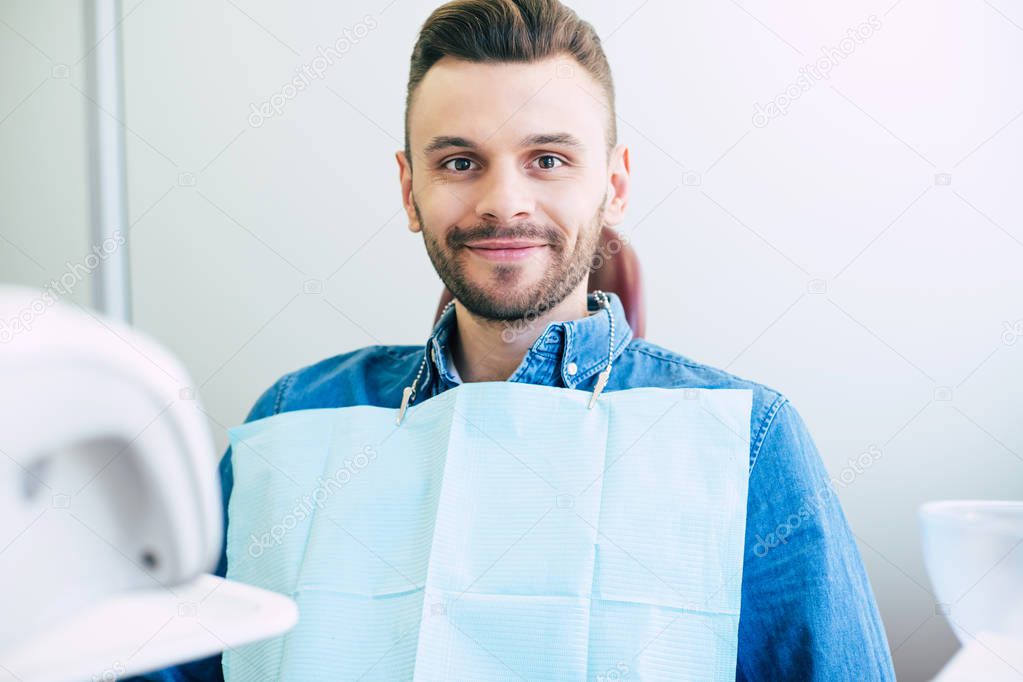Feel fine. A man on the dental appointment in a professional clinic is ready to have a treatment without any pain and with perfect final result.