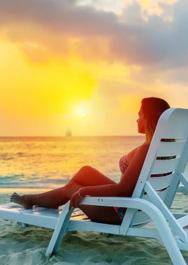 An hissi. Salonda beyaz pürüzsüz kum ve bronzlaşmış kız ile plajın yakınında okyanusun arkasında akşam turuncu güneş.