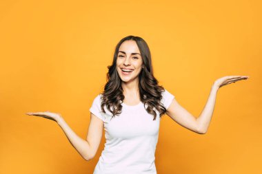 Gevşemiş! Kalın kahverengi ve kıvırcık saçlı jiggish hilariously güzel kız, onun yüzünde mükemmel beyaz gülümseme jest ve mimik yoluyla duygularını dile getiriyor.