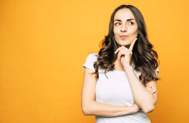 Düşünmeme izin ver. Musing güzel kızın yanında temel kıyafet turuncu arka planda bir şey hakkında düşünme ve biz onun hareketleri ile görmek ve taklit.