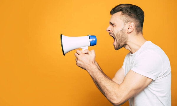 Кричал на весь голос. Портрет бокового вида с мегафоном в руке эмоционального, спортивного человека, который показывает свой гнев через крик
.