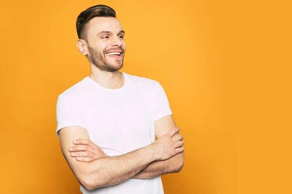 Best way. Handsome man with a brilliant smile on his young pretty face, great hairstyle and casual outfit neat the spice-orange background