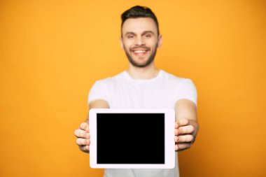 Yakışıklı genç adam kamera ve gülümseyerek elinde tablet boş ekran gösteriyor