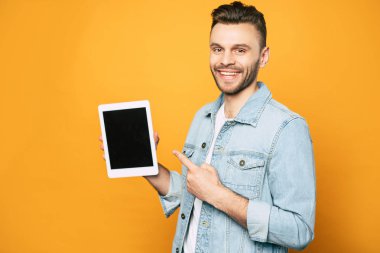 Sarı arka plan üzerinde elinde modern tablet ile rahat iş adamı yan görünüm portresi