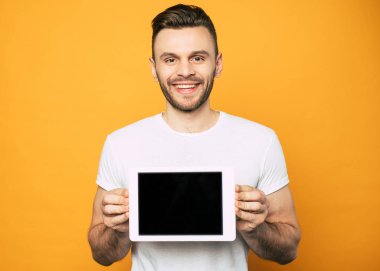 Yakışıklı genç adam kamera ve gülümseyerek elinde tablet boş ekran gösteriyor