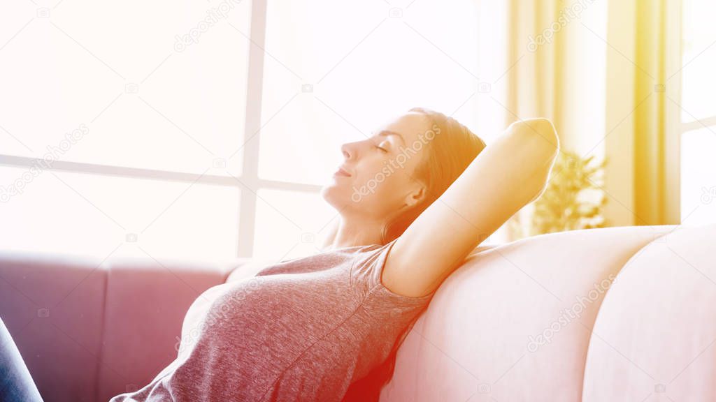 Close up side view photo of beautiful young woman while relaxing on the couch at home with closed eyes