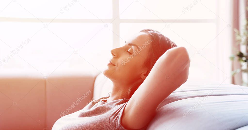 Close up side view photo of beautiful young woman while relaxing on the couch at home with closed eyes