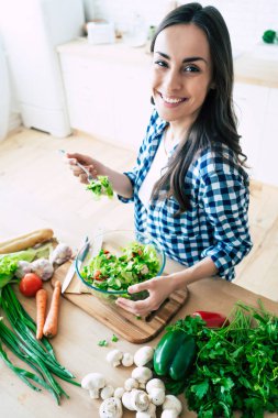 Sağlıklı yaşam tarzı. Güzel bir hayat. Organik gıda. Sebze. O evde mutfakta lezzetli vegan salata çalışırken mutlu sevimli güzel genç kadının portresi kadar yakın.