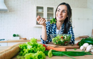 Sağlıklı yaşam tarzı. Güzel bir hayat. Organik gıda. Sebze. O evde mutfakta lezzetli vegan salata çalışırken mutlu sevimli güzel genç kadının portresi kadar yakın.