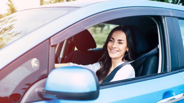 Güzel bayan sürücü arabada oturuyor.