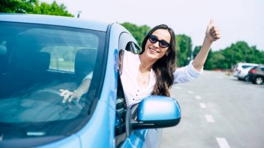 Gülümseyen kadın sürücü arabadan başparmak gösteren