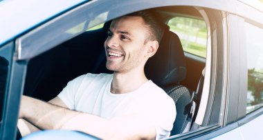 Arabada oturan yakışıklı gülümseyen erkek sürücü